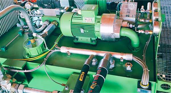 Pumpen- und Motoreinheit mit Rohrleitungen auf einem grünen Hydraulikbehälter
