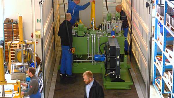 Mitarbeiter beim Aufbau eines großen grünen Hydraulikaggregats in der Werkstatt